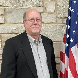 Director Steve Witt standing next to an American Flag